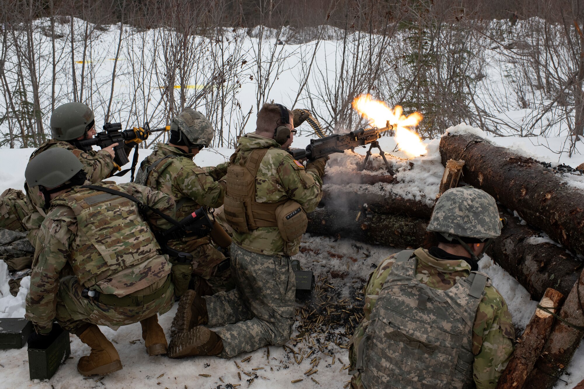 Airmen take cover behind an arctic defensive fighting position.