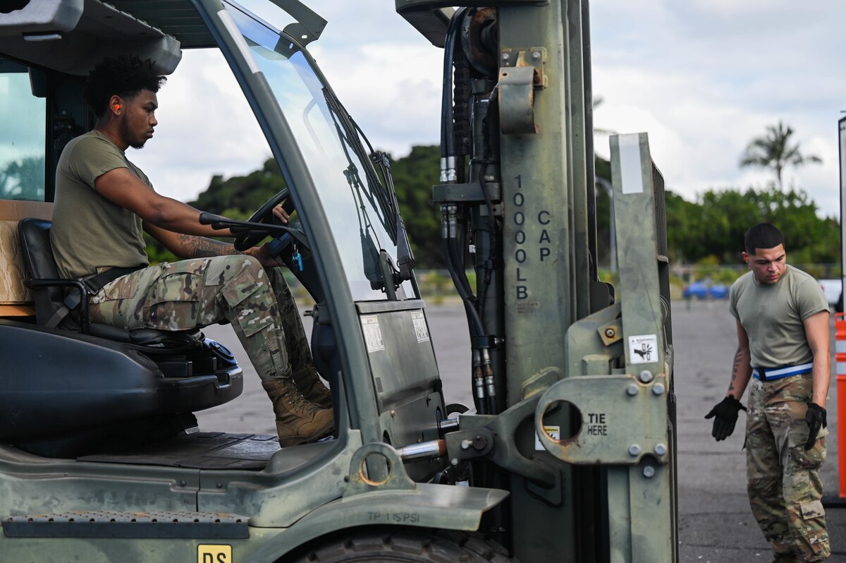 Airman 1st Class Justin Marcano and Airman 1st Class Jaylen Alberts, 647th Logistics Readiness Squadron ground transportation journeymen, communicate while maneuvering 15th Maintenance Group equipment during Exercise TROPIC FURY at Joint Base Pearl Harbor-Hickam, Hawaii, March 1, 2022. The 15th Wing’s ability to ready Airmen and aircraft for airlift operations was tested during the exercise. (U.S. Air Force photo by Staff Sgt. Alan Ricker)