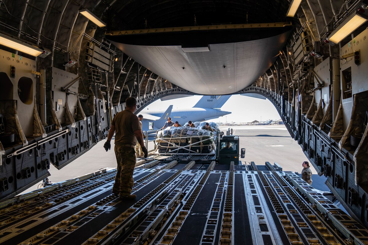 Airmen from the 535th Airlift Squadron work alongside the 647th Logistics Readiness Squadron combat mobility flight to load cargo from a Tunner 60K aircraft cargo loader/transporter onto a C-17 Globemaster III during Exercise TROPIC FURY at Joint Base Pearl Harbor-Hickam, Hawaii, March 2, 2022. The Tunner 60k can hold up to 60,000 lbs of cargo and allows Airmen to safely and effectively transport and load cargo onto aircraft. (U.S. Air Force photo by Airman 1st Class Makensie Cooper)