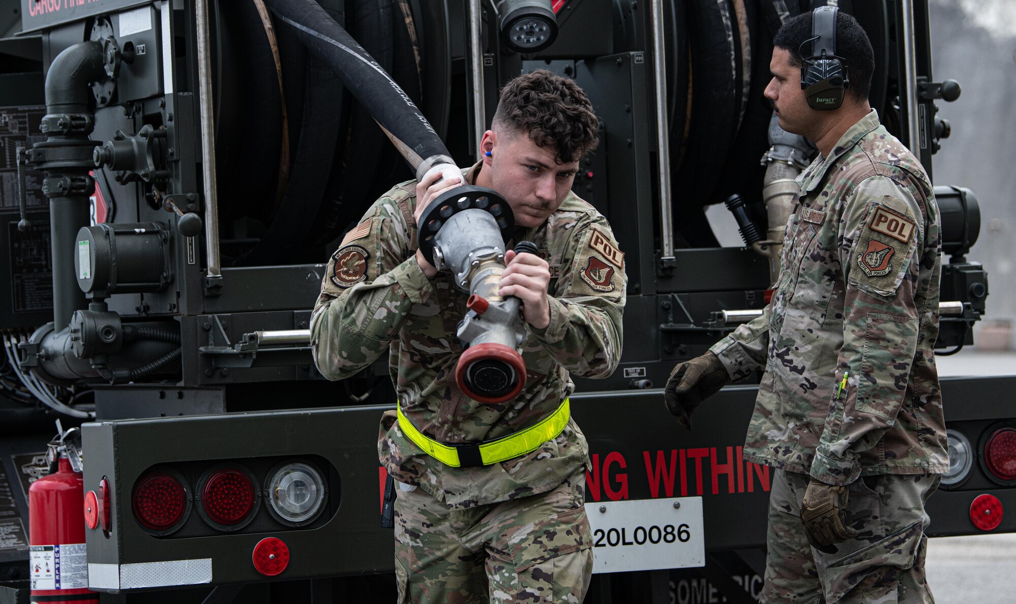 Airmen carries refueling hose.