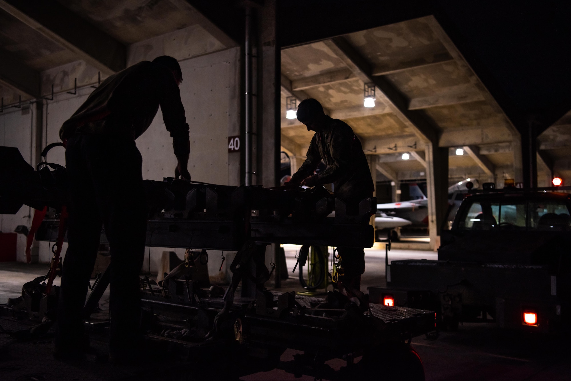 Airmen download munitions from a F-15C Eagle at dusk.