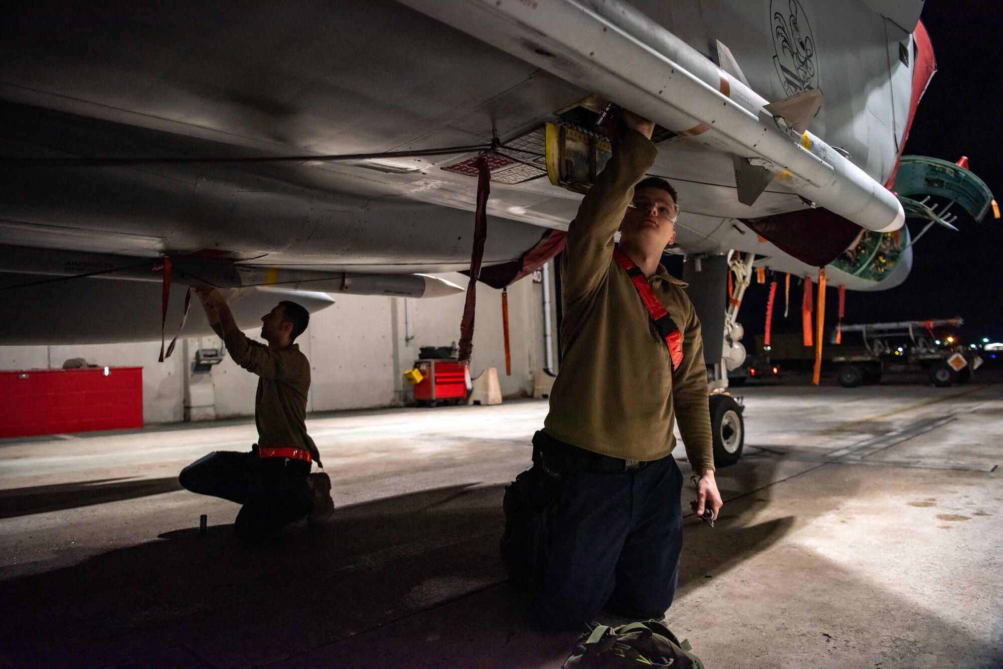 Airmen download munitions from a F-15C Eagle at dusk.