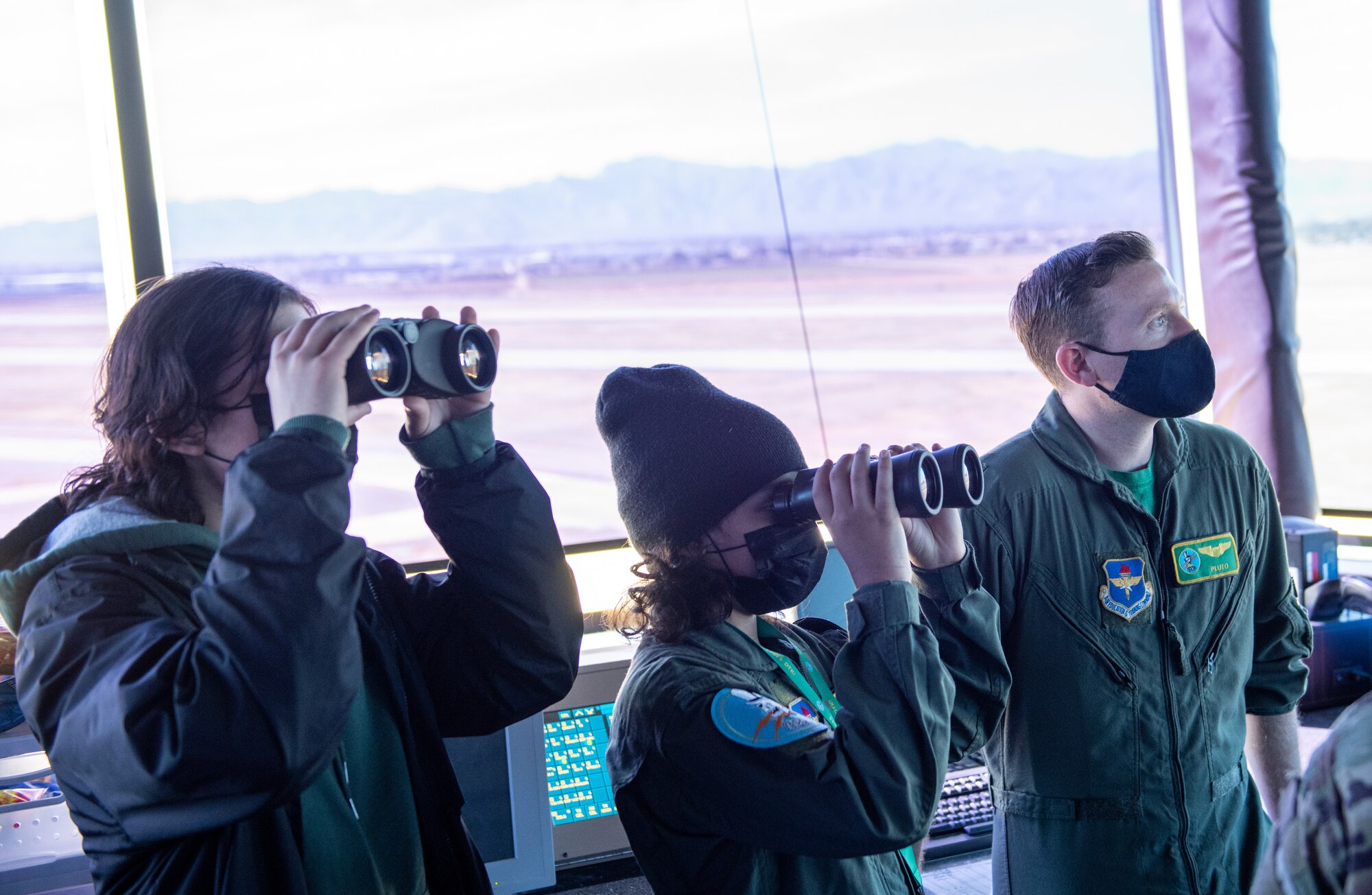 Ian “Monky Warrior” Brito (center), Pilot for a Day participant, looks out at the flightline from the Air Traffic Control tower Feb. 25, 2022, at Luke Air Force Base, Arizona.