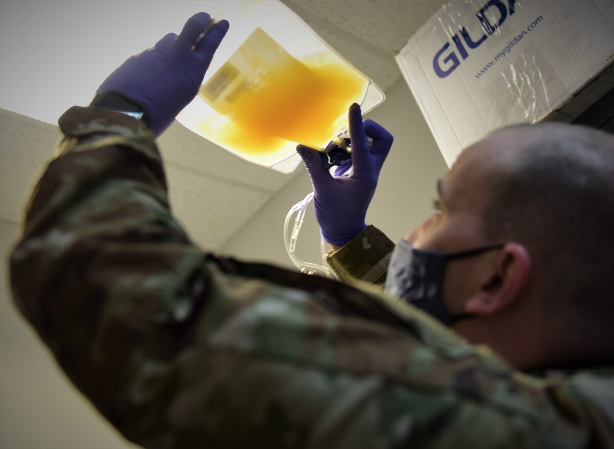 Military member looks at medical sample through under light.