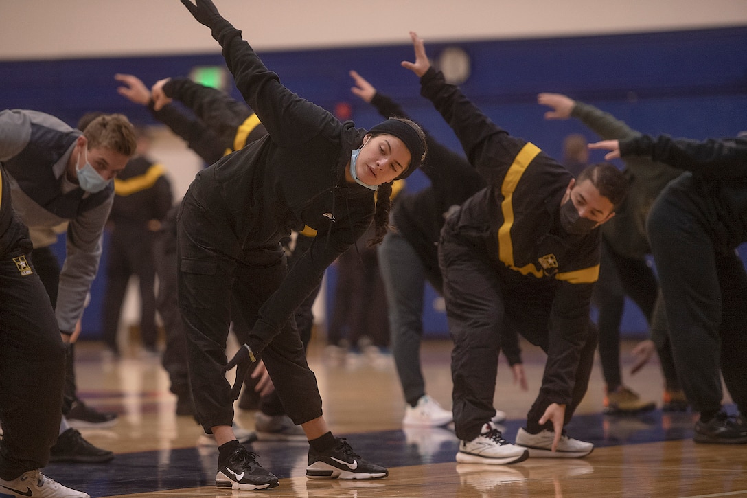 Army cadets stretch in an open gym.