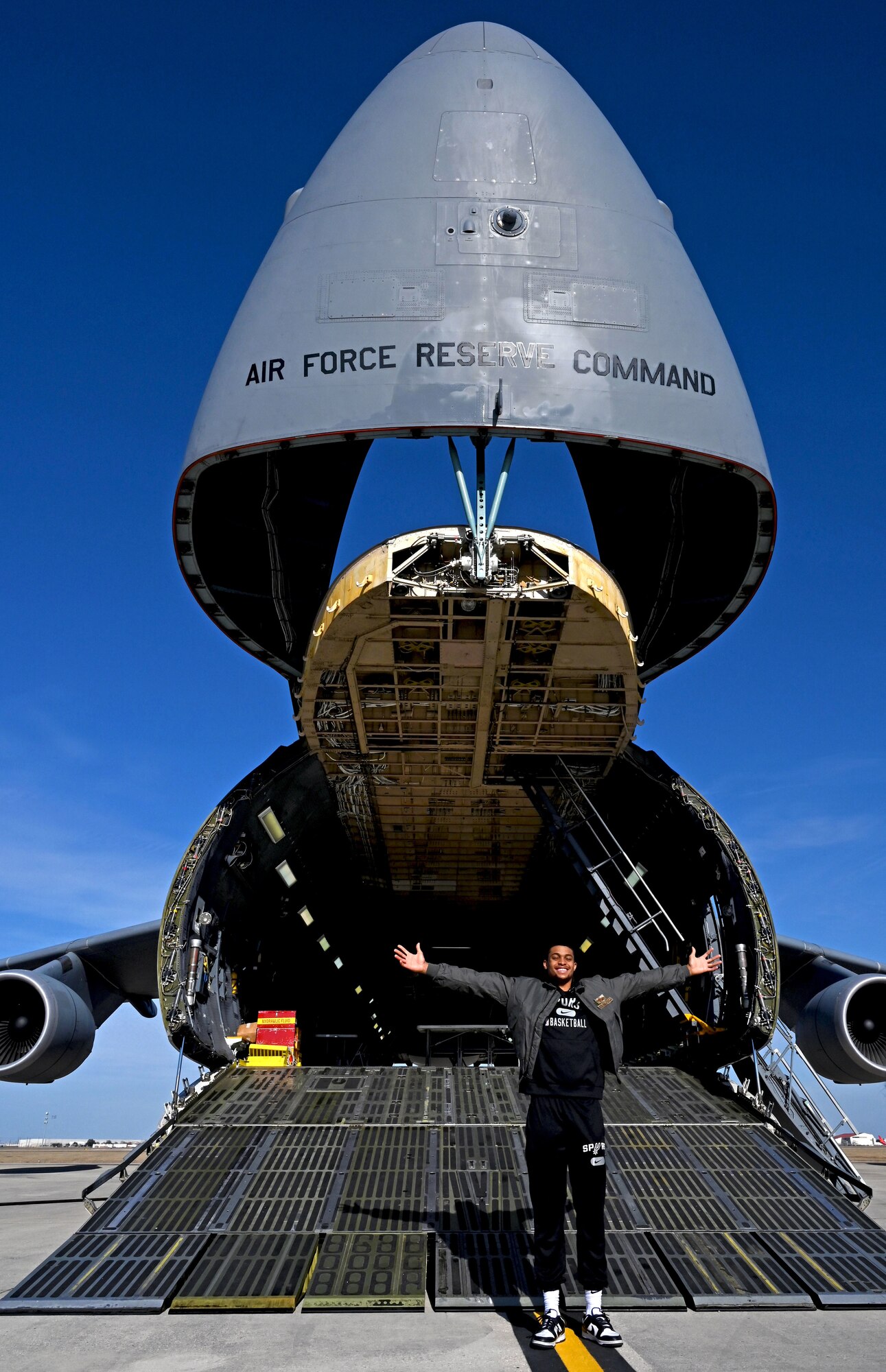 Keldon Johnson, a San Antonio Spurs basketball player, stands for a photograph with a C-5M Super Galaxy aircraft during his visit to the 433rd Airlift Wing at Joint Base San Antonio-Lackland, Texas, March 2, 2022. (U.S. Air Force photo by Samantha Mathison)