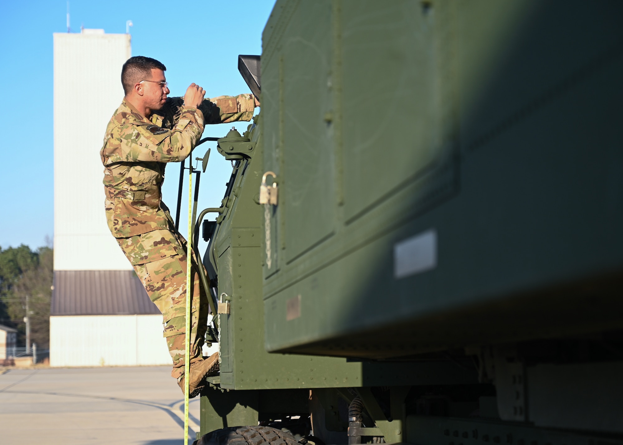 A loadmaster from the 41st Airlift Squadron measures a High Mobility Artillery Rocket System before it is loaded onto a C-130J Super Hercules