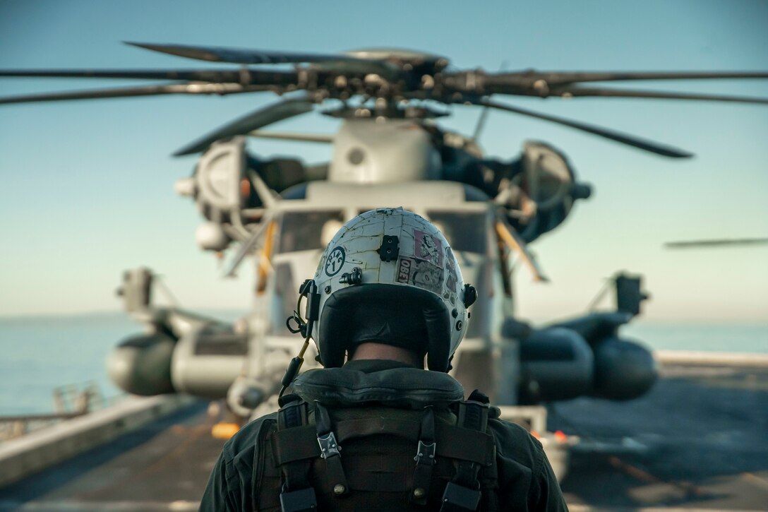 A U.S. Marine Corps CH-53E Super Stallion crew chief assigned to Marine Medium Tiltrotor Squadron 165, 11th Marine Expeditionary Unit, conducts preflight procedures with a Super Stallion during the squadron’s flyoff from the amphibious transport dock USS Portland (LPD 27), Feb. 28, 2022. Marines and Sailors of the 11th MEU and Essex Amphibious Ready Group are underway conducting routine operations in U.S. 3rd Fleet.