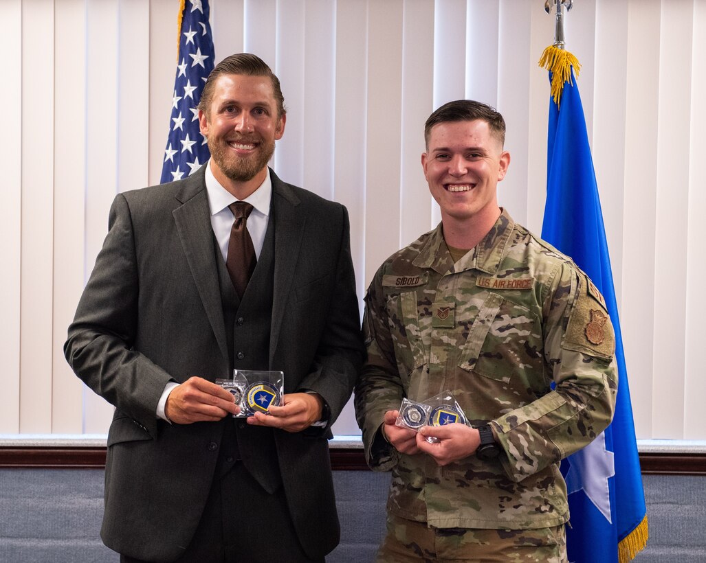 Special Agent Michael Robinette, left, and Staff Sgt. Phillip Sibold were coined by Brig. Gen. Terry L. Bullard, Office of Special Investigations commander, March 2, 2022, for their heroic actions during an off-base domestic violence incident near Patrick Space Force Base, Florida. The November 2021 incident resulted in one man charged with attempted murder of a woman who was severely injured. (Department of the Air Force photo by Amanda Inman, 45SW/PA-BMM)