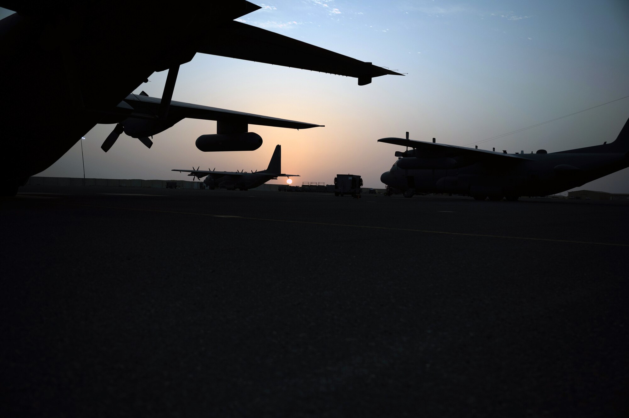 U.S. Air Force C-130 Hercules aircraft sit on the flightline during sunset