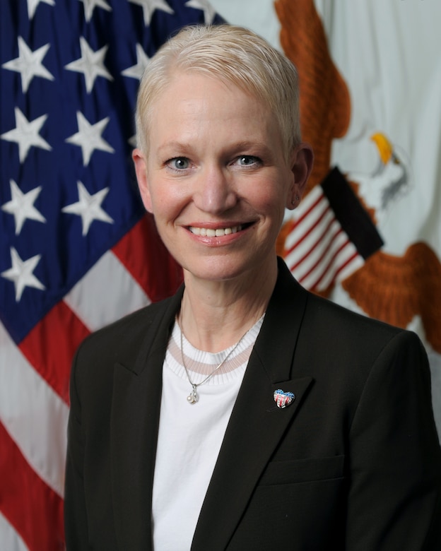 Woman stands in front of flag.