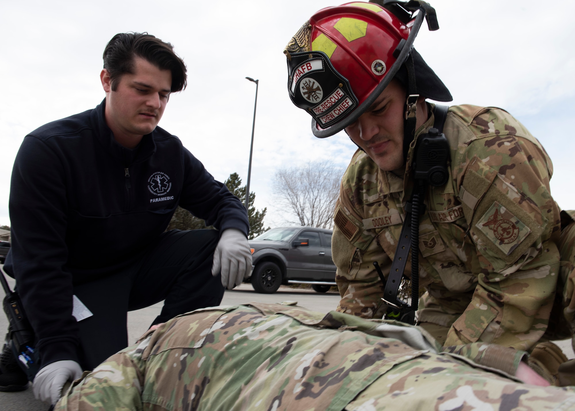 Two Airmen inspect the simulated, injured body of another Airman.