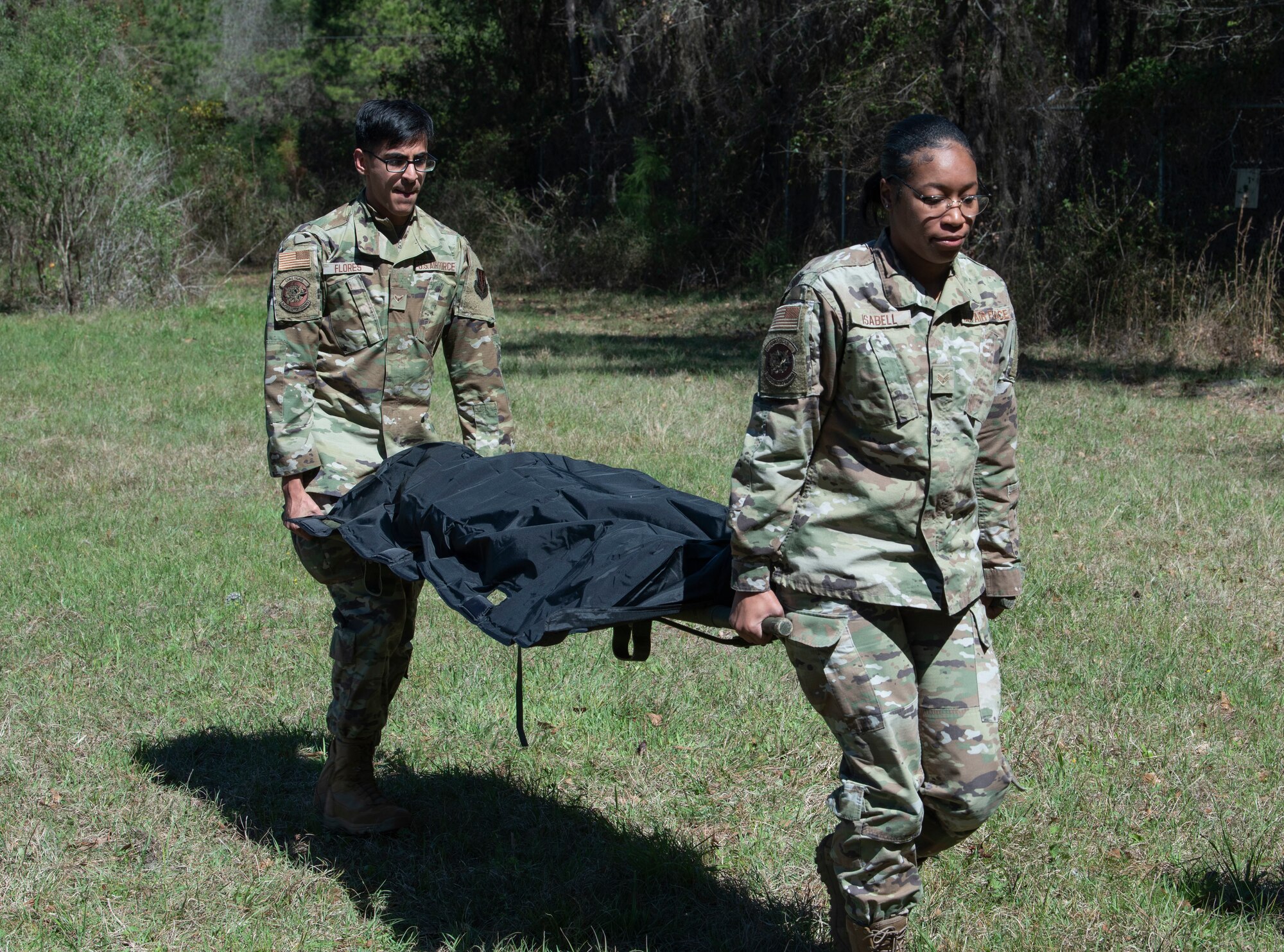 Airman 1st Class Victor Flores, 23rd Force Support Squadron fitness apprentice (Left) and Senior Airman Deairra Isabell, 23rd FSS fitness journeyman (Right), carry a simulated casualty during exercise Ready Tiger 22-01 at Moody Air Force Base, Georgia, March 2, 2022. Collecting and reporting casualties helps mission commanders track manpower and make appropriate mission decisions. (U.S. Air Force photo by Senior Airman Thomas Johns)