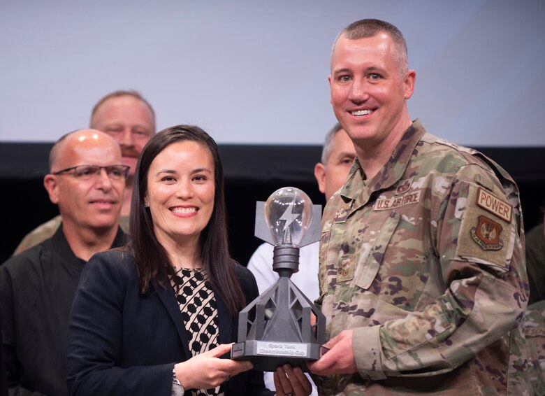 Under Secretary of the Air Force Gina Ortiz Jones presents Senior Master Sgt. Brent Kenney, 52nd Fighter Wing, Spangdahlem Air Base, Germany, the Spark Tank 2022 trophy at the Air Force Association’s Warfare Symposium in Orlando, Fla., March 4, 2022. Kenney’s winning idea, “Project Arcwater,” is a simple, green, expedited way to save energy and provide drinking water by using solar fabric and environmental water harvesting in an agile combat employment. (U.S. Air Force photo by Tech. Sgt. Armando A. Schwier-Morales)