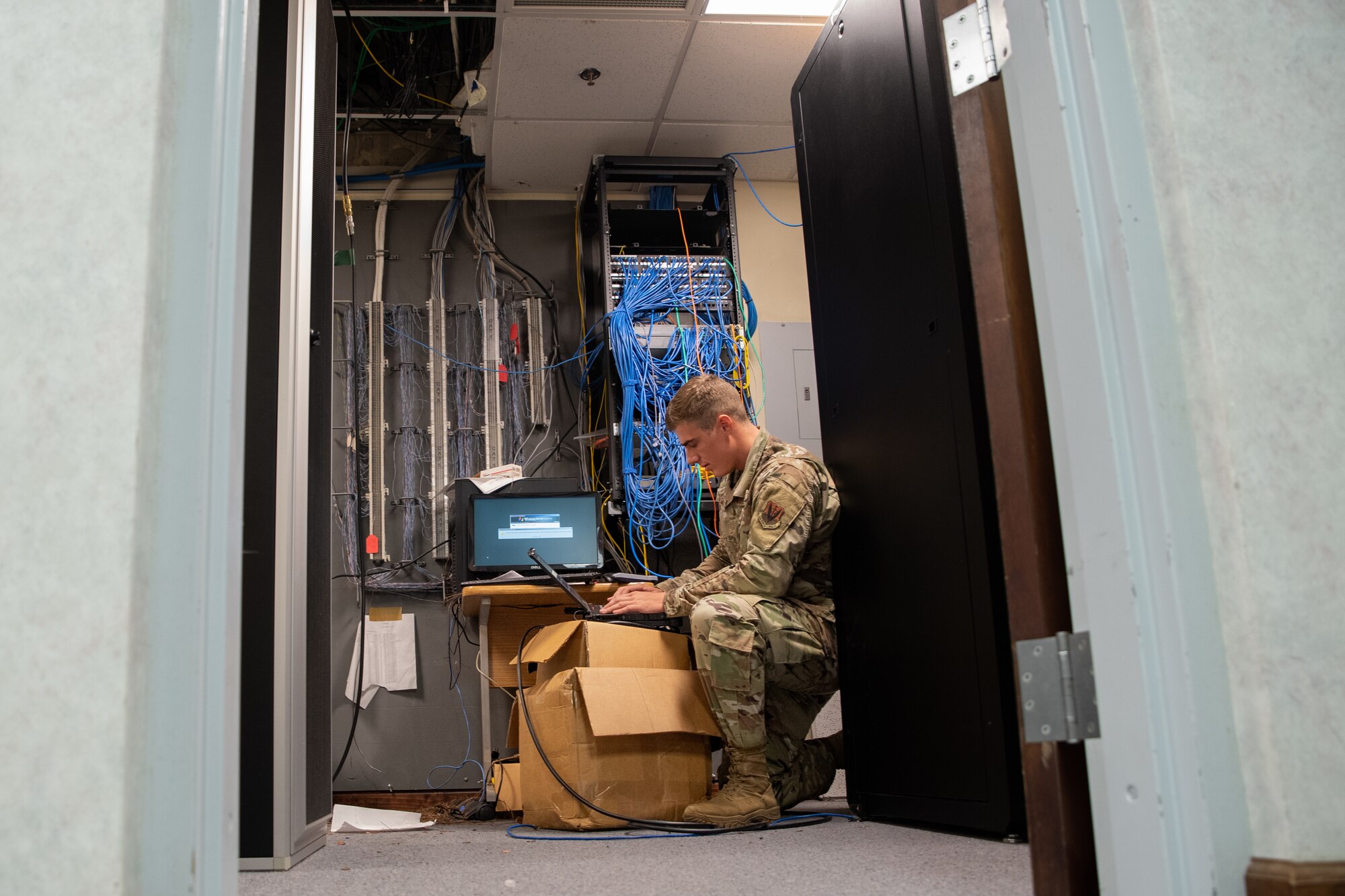 U.S. Air Force Airman 1st Class Jacob Stahleker, 23rd Communications Squadron S9 technician, connects ethernet cables to set up the Wing Operations Center for exercise Ready Tiger 22-01 at Moody Air Force Base, Georgia, Feb. 24, 2022. The Wing Operations Center and the Air Operations Center interact to generate air tasking orders and employ combat air power. (U.S. Air Force photo by Andrea Jenkins.)