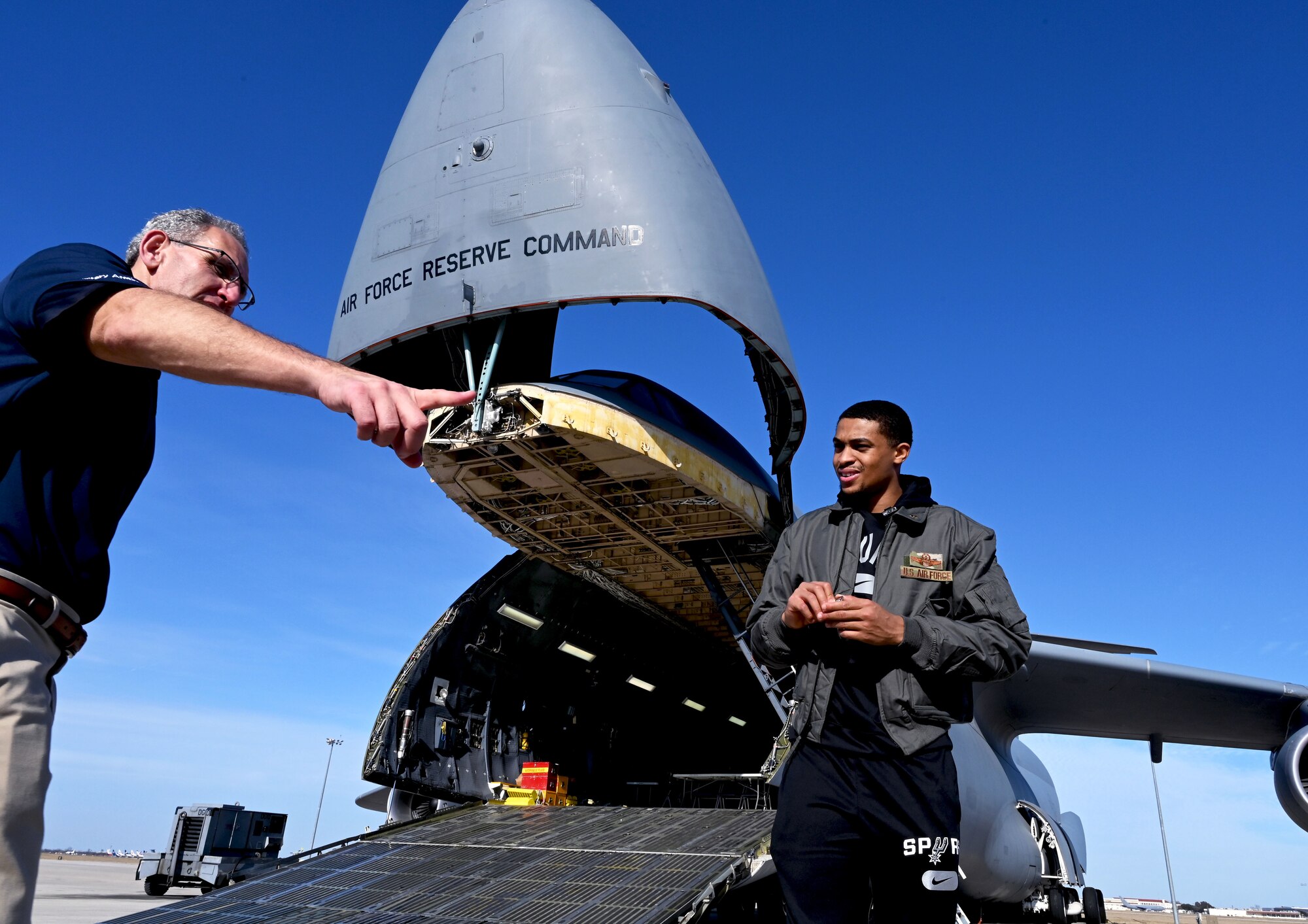 Keldon Johnson, a San Antonio Spurs basketball player, talks with Dan Mishket, USAA senior military affairs representative and field operations-south region, during his visit to the 433rd Airlift Wing at Joint Base San Antonio-Lackland, Texas, March 2, 2022. Johnson received an in-depth look at the missions and capabilities of an Air Force Reserve Command C-5M Super Galaxy aircraft. (U.S. Air Force photo by Samantha Mathison)