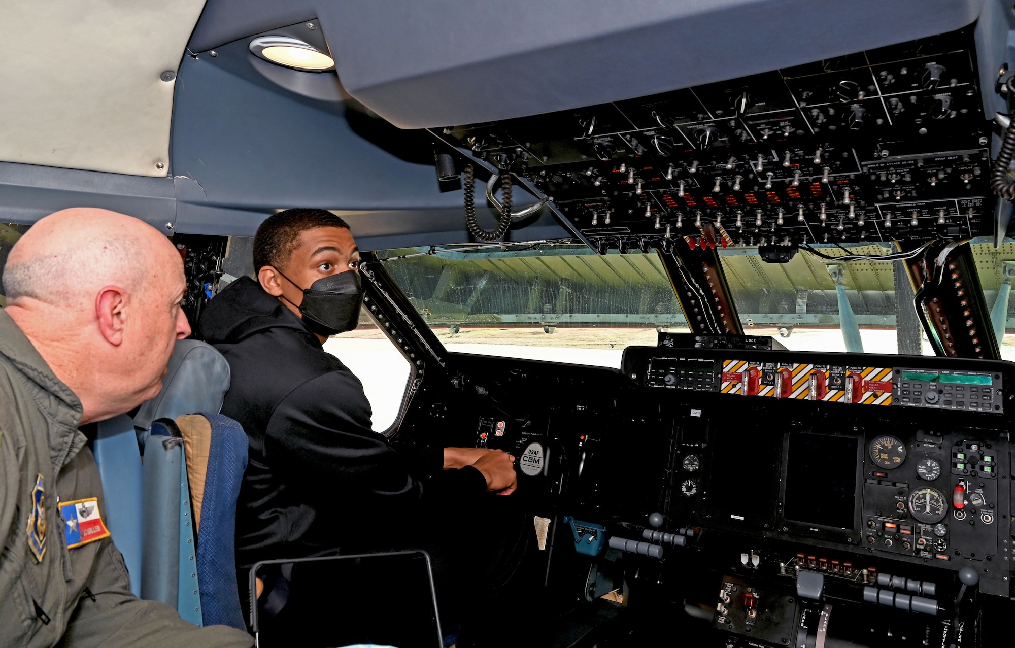 Keldon Johnson, a San Antonio Spurs basketball player, sits in the pilot seat of a C-5M Super Galaxy aircraft during his visit to the 433rd Airlift Wing at Joint Base San Antonio-Lackland, Texas, March 2, 2022. Col. James Miller, 433rd Operations Group commander, explained the functions and capabilities of the aircraft to Johnson during the tour. (U.S. Air Force photo by Samantha Mathison)
