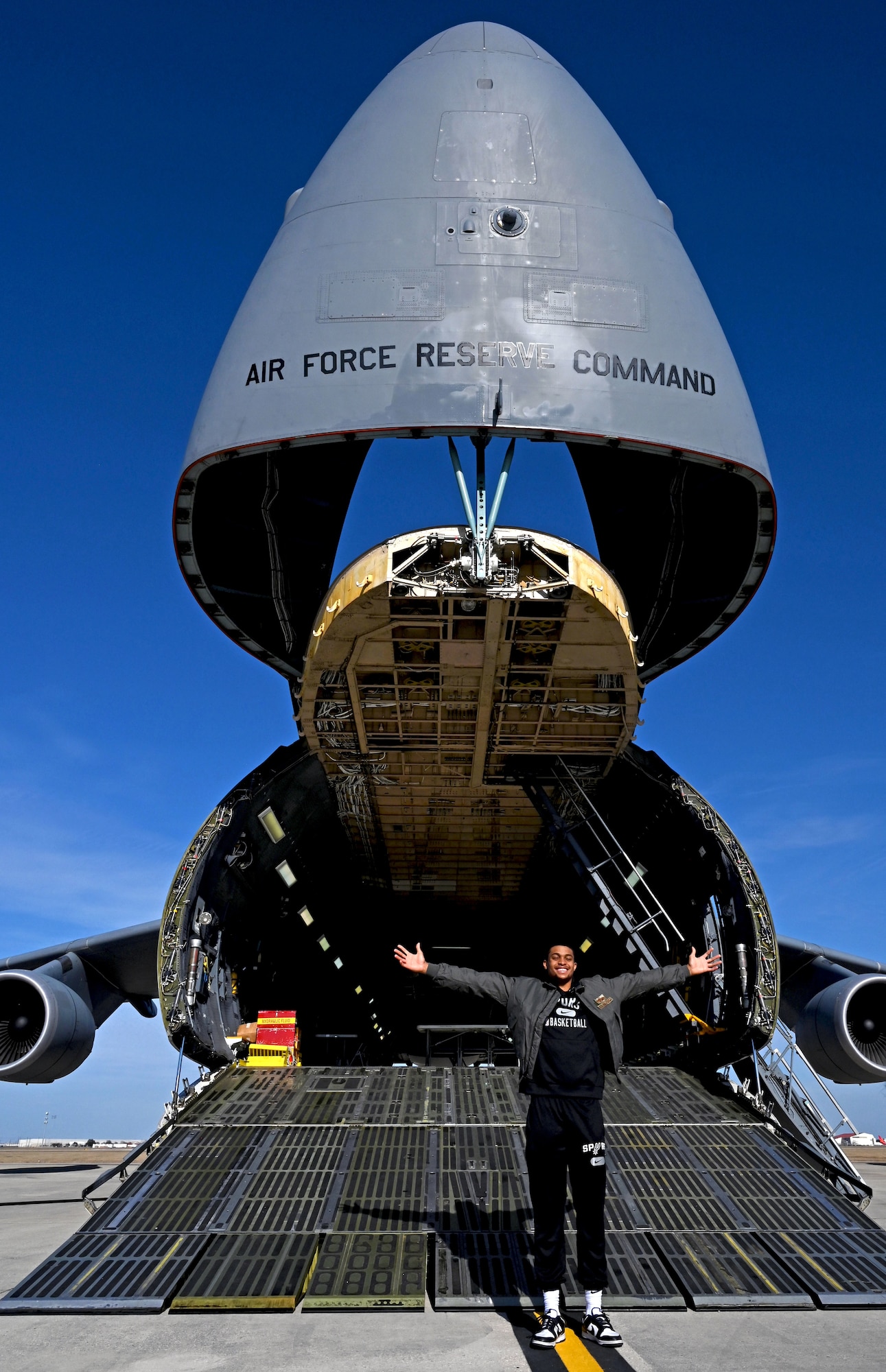 Keldon Johnson, a San Antonio Spurs basketball player, stands for a photograph with a C-5M Super Galaxy aircraft during his visit to the 433rd Airlift Wing at Joint Base San Antonio-Lackland, Texas, March 2, 2022. (U.S. Air Force photo by Samantha Mathison)
