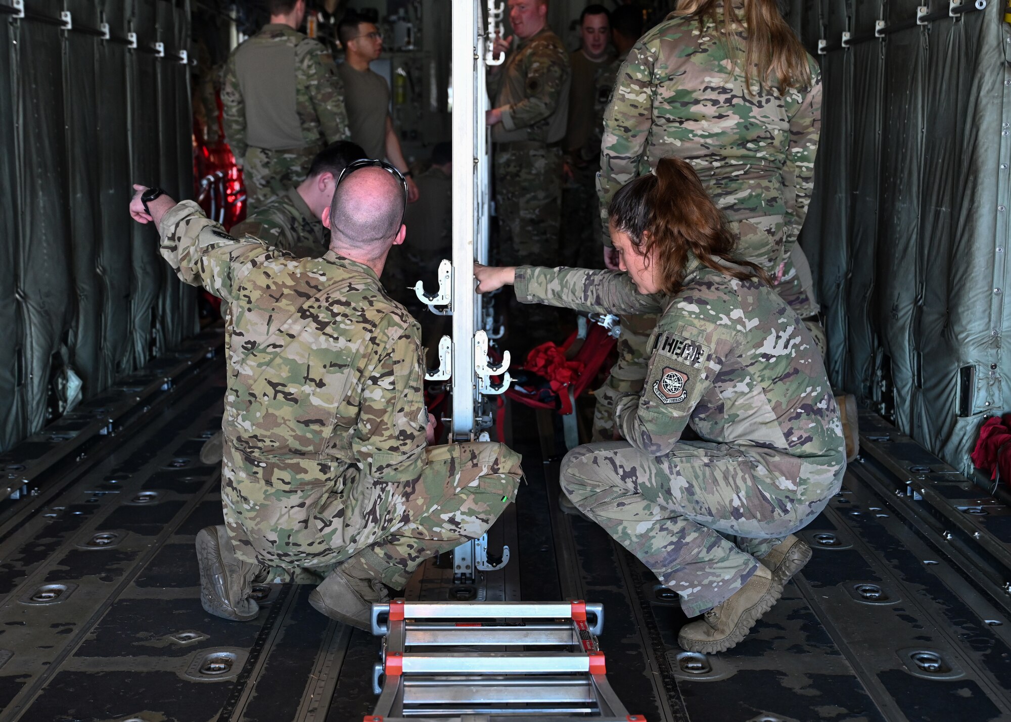 Loadmasters and pilots from the 41st Airlift Squadron work together to set up chairs in a C-130J Super Hercules