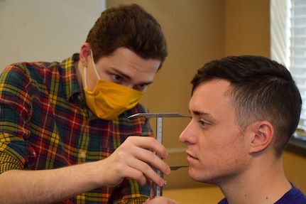 Rex Weinstein, Air Force Life Cycle Management Center Human Systems Division Airmen Accommodation Laboratory contractor, takes facial measurements of Tech. Sgt. Thomas Karren, 343rd Training Squadron Security Forces Academy instructor, at Joint Base San Antonio-Lackland, Texas, Feb. 28, 2022. (U.S. Air Force photo by Airman Mark Colmenares)