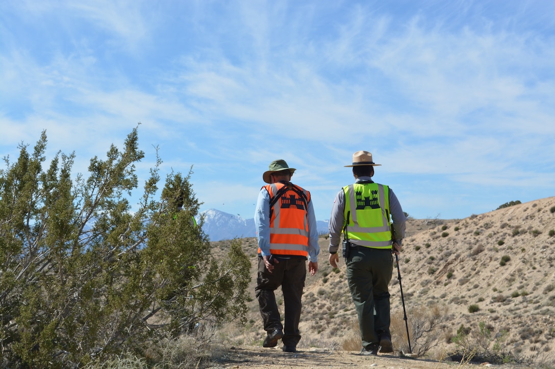 LA District Biologist Jon Rishi, left, and LA District Park Ranger Henry Csaposs, right, hike along a trail March 2 at the Mojave River Dam in San Bernardino County, California.