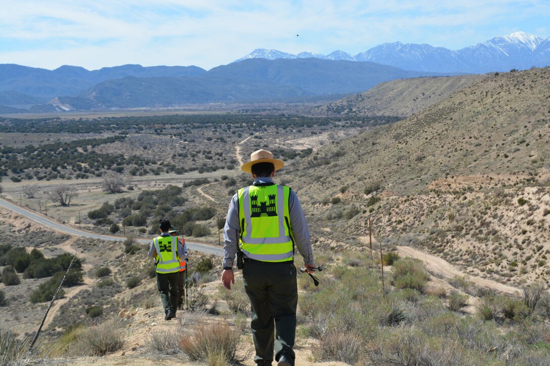 LA District Biologist Jon Rishi, background, and LA District Park Rangers Connie Chan Le, middle, and Henry Csaposs, foreground, hike along a trail March 2 at the Mojave River Dam in San Bernardino County, California.