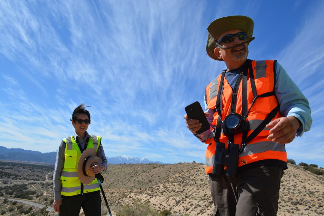 LA District Park Ranger Connie Chan Le, left, and LA District Biologist Jon Rishi, right, stop to take a picture of a California Poppy flower while hiking along a trail March 2 at the Mojave River Dam in San Bernardino County, California.