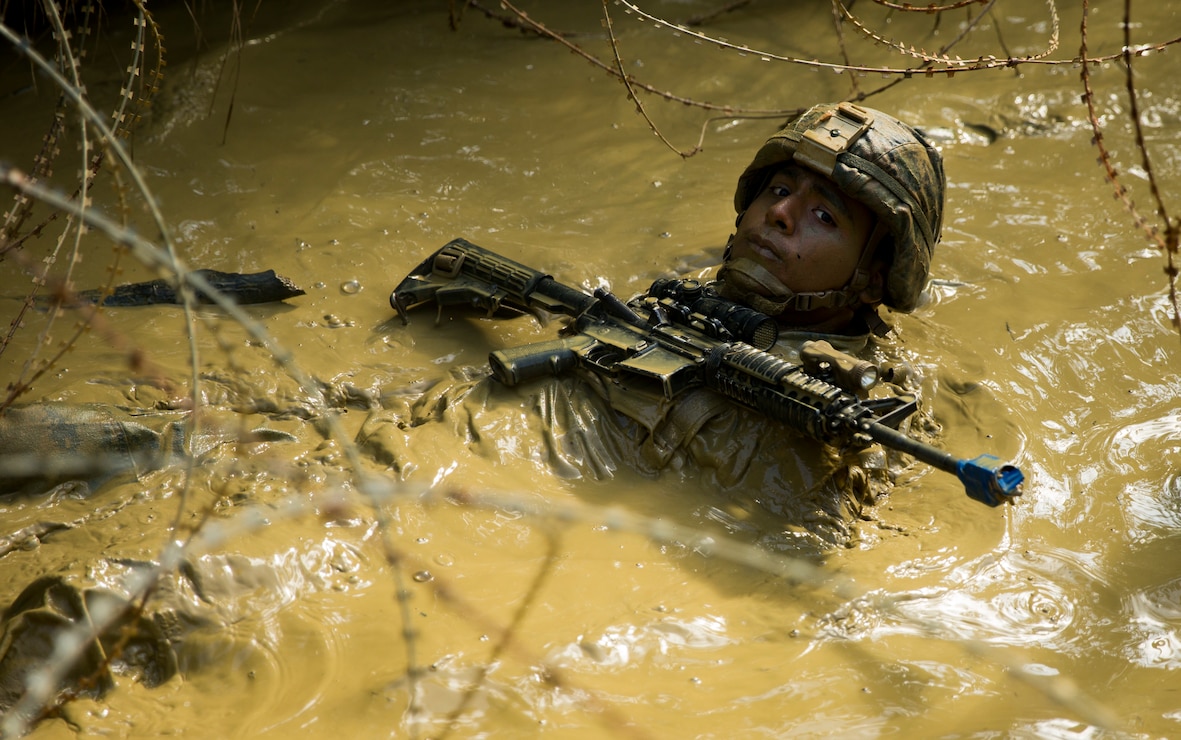 Cpl. Marcos Valencia maneuvers through a mud pit during the endurance course at the Jungle Warfare Training Center in Okinawa, Japan, Jan. 15, 2018. JWTC prepares Marines for operations in a jungle environment. Valencia, a Live oak, California native, is a team leader with India Company. 3rd Battalion, 3rd Marine Regiment, 3rd Marine Division. The mission of 3/3 Marines is to train and conduct theater security cooperation across the Pacific command area of responsibility in order to ensure access, deter threats, and build capacity with allies in the region, as well as being prepared to conduct crisis response and combat operations. (U.S. Marine Corps photo by Sgt. Ricky Gomez)