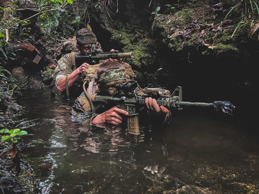 Green Berets with 1st Battalion, 1st Special Forces Group (Airborne) alongside their Marine counterpart move through a swamp during the 4th Marine Regiment Jungle Warfare Exercise at the Jungle Warfare Training Center, May 23, 2021. The exercise includes forward reconnaissance, terrain analysis, practice using a variety of communication platforms, small unit tactics and patient extraction procedures.