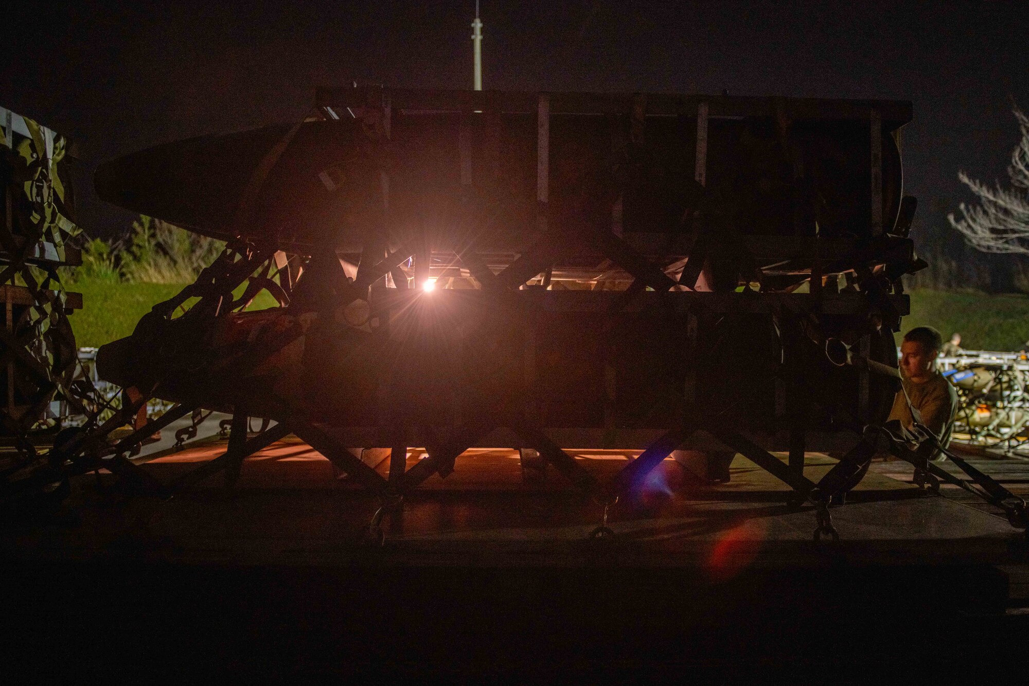 A pallet of four bombs is loaded on the back of a truck at night