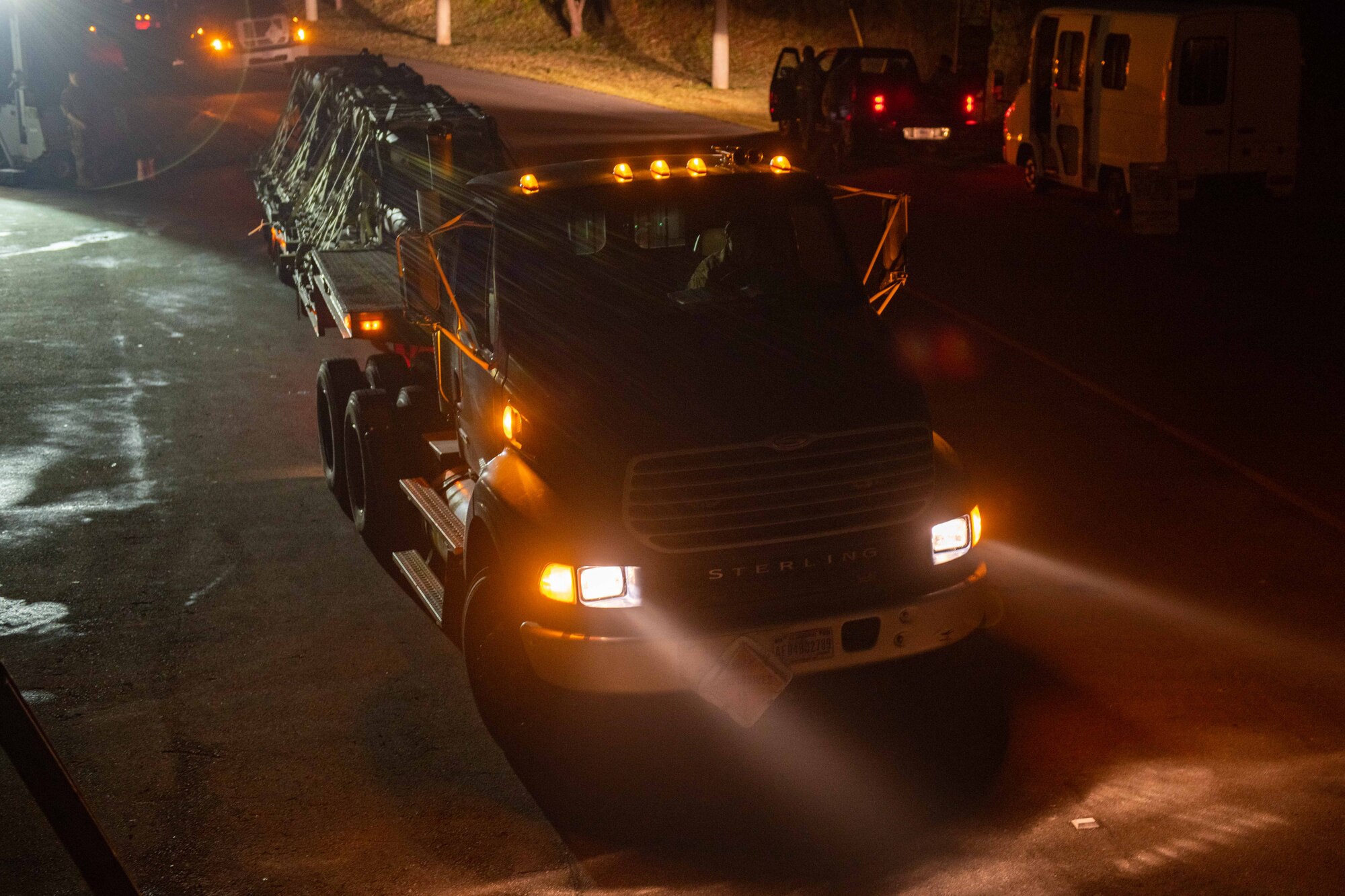 A truck pulls away with a bunch of munitions loaded in the back at night