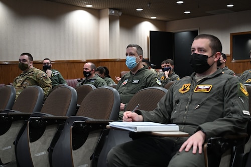 Airmen in flight suits sitting in lecture room