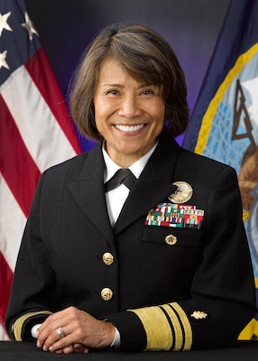 Offical portrait photo of smiling woman in her uniform with USA and Navy flag in background