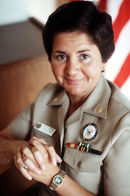 Higher view portrait of woman in beige uniform smiling at camera with usa flag in background