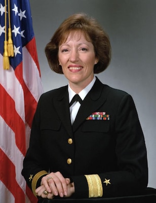 Official portrait of smiling woman in her uniform with USA flag in background