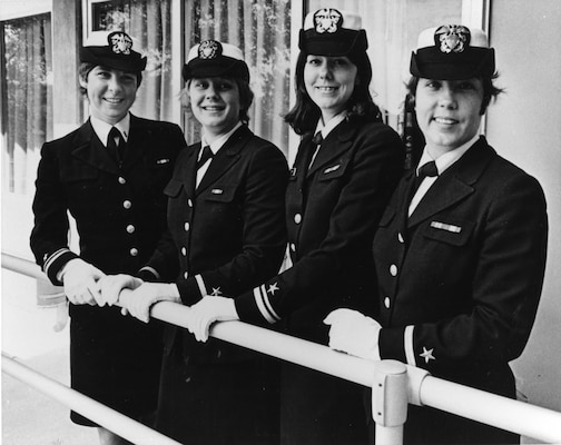 Black and white photo of 4 women in their uniform smiling at camera