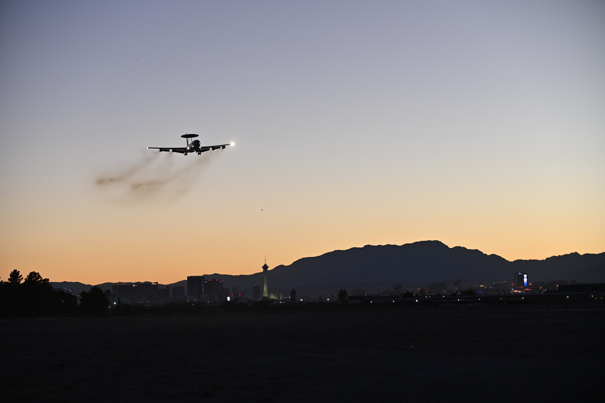 E-3A aircraft lands at sunset against the Las Vegas skyline.