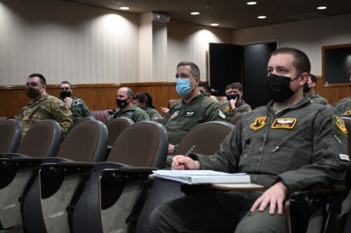 Airmen in flight suits sitting in lecture room