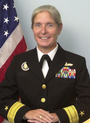 Offical portrait of woman in her uniform smiling with USA flag in background