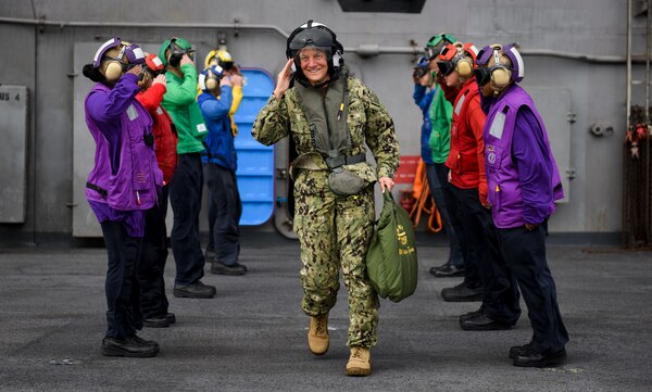 Vice adm Nora tyson, woman in her uniform walking through 2 lines of sailors smiling