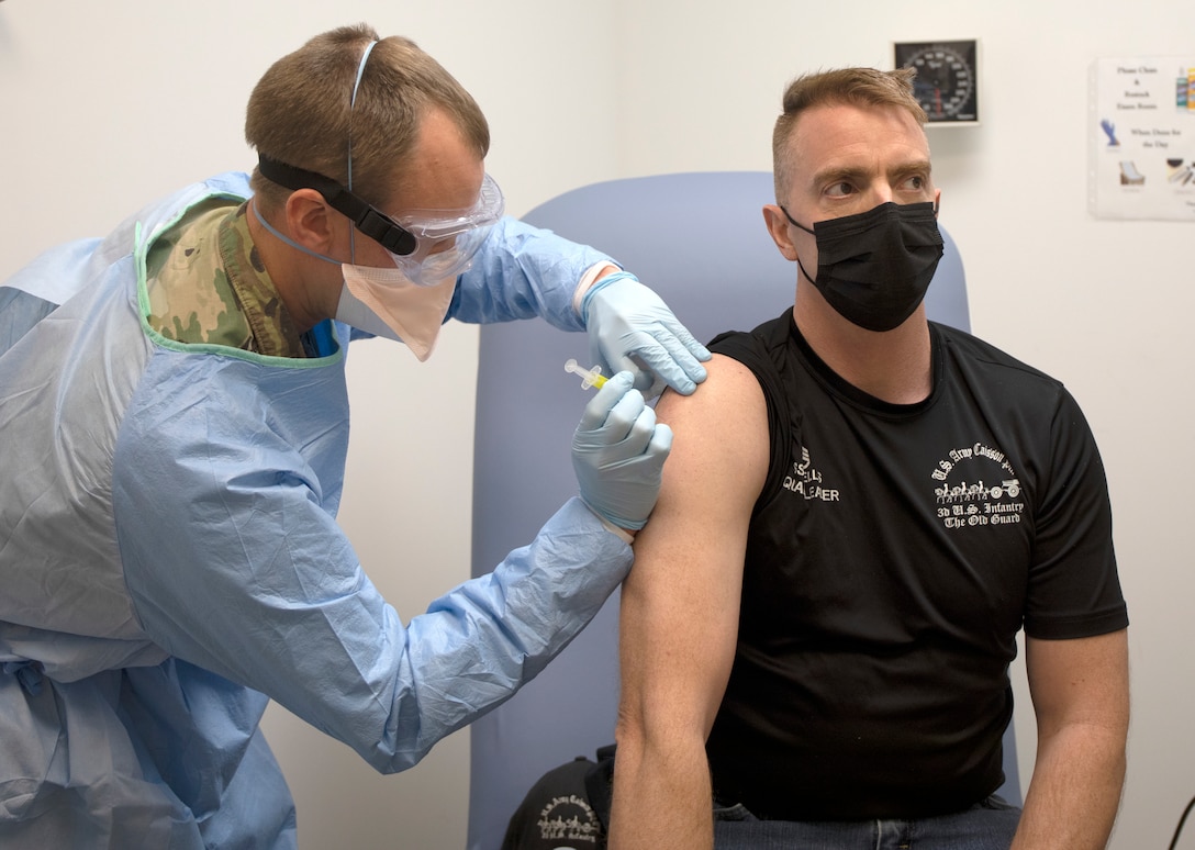 Army Capt. Aaron Sanborn injects Staff Sgt. Daniel Ellis during clinical testing for WRAIR's spike ferritin nanoparticle (SpFN) vaccine at the WRAIR Clinical Trials Center.