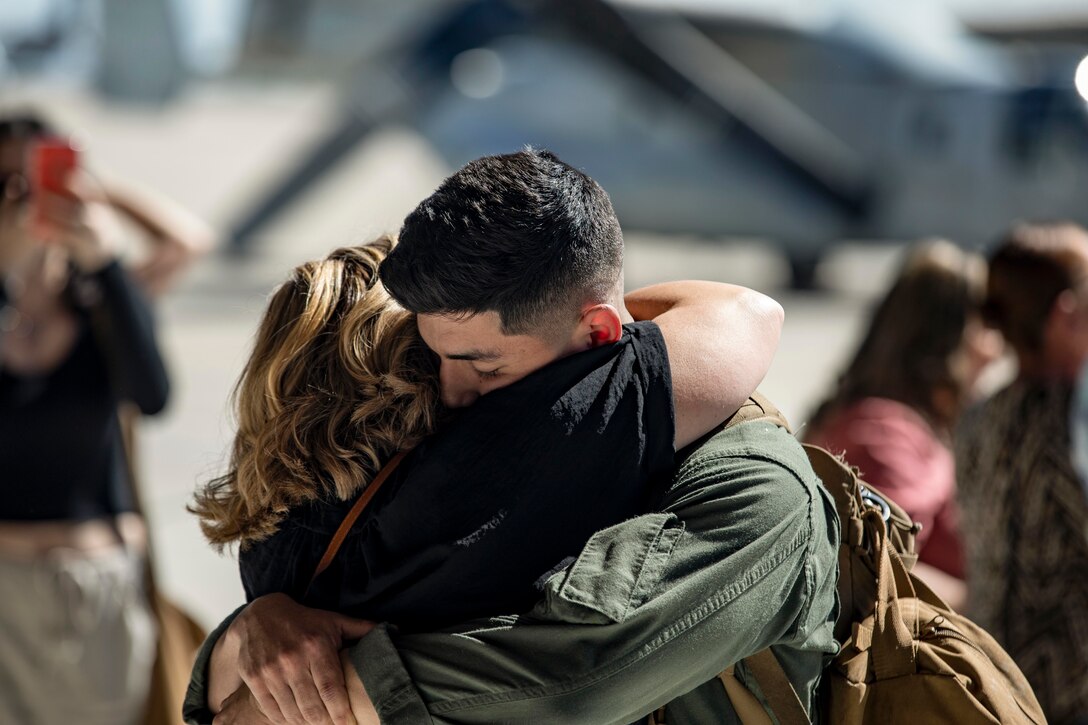 A Marine hugs a family member.