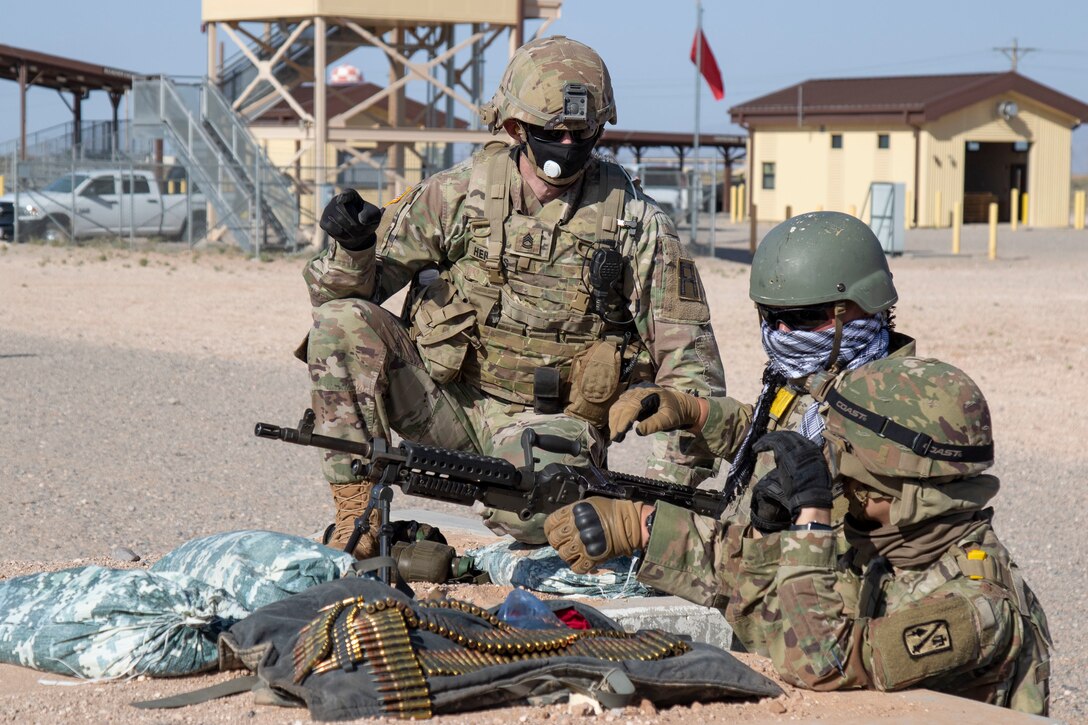 Sgt. 1st Class Zachary Hermes, right, an Observer Coach/ Trainer assigned to 2nd Battalion, 362nd Field Artillery Regiment, 5th Armored Brigade, First Army Division West discusses best practices while Staff Sgt. Sean Eckrote, center, and Spc. Maison Millan, right, assigned to Bravo Battery, 1st Battalion, 158th Field Artillery Regiment, Oklahoma National Guard, prepare to fire an M240B machine gun at McGregor Range Complex, N.M., May 09, 2020.