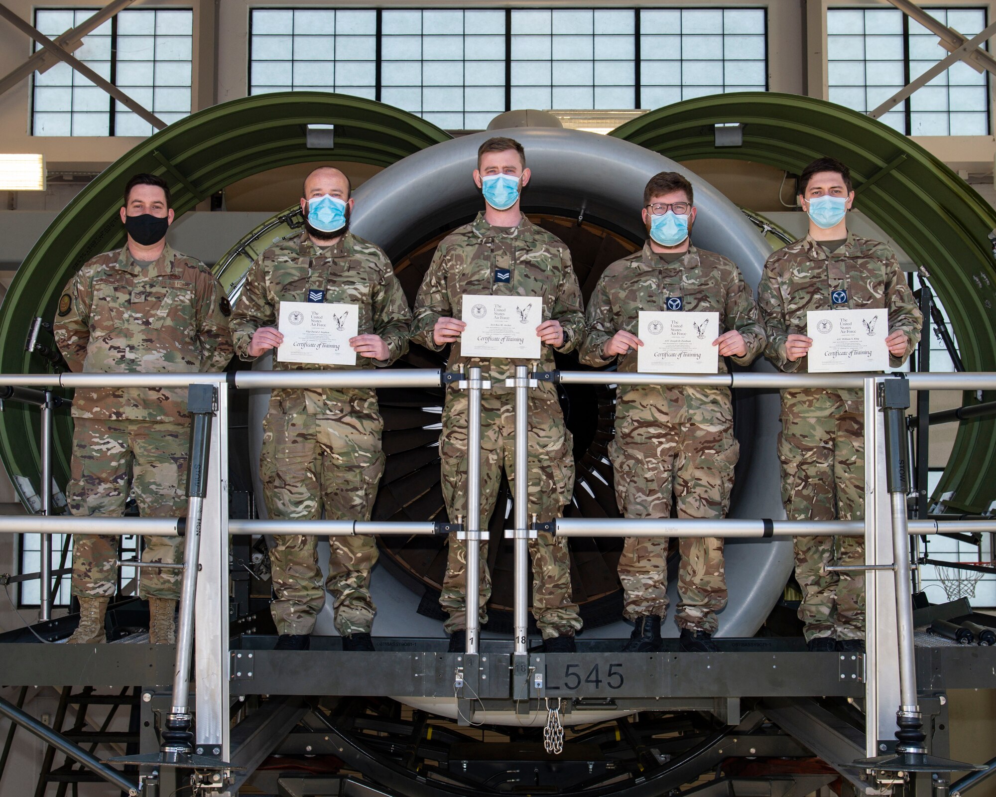 Left to right, Tech. Sgt. Thomas Rogers, 373rd Training Squadron, Detachment 3 C-17 propulsion instructor, stands with Royal Air Force members Sgt. David Stephen, Cpl. Ben Archer, Senior Aircraftman Technician Joseph Eastham and William King, all C-17 Globemaster maintainers from 99 Squadron, RAF Brize Norton, United Kingdom, as they hold their course certificates at Dover Air Force Base, Delaware, Feb. 15, 2022. Using an engine mock-up trainer, the British maintainers attended the 64-hour C-17 Engine Change course where they learned how to safely remove and reinstall the Pratt & Whitney F117-PW-100 turbofan engine. (U.S. Air Force photo by Roland Balik)