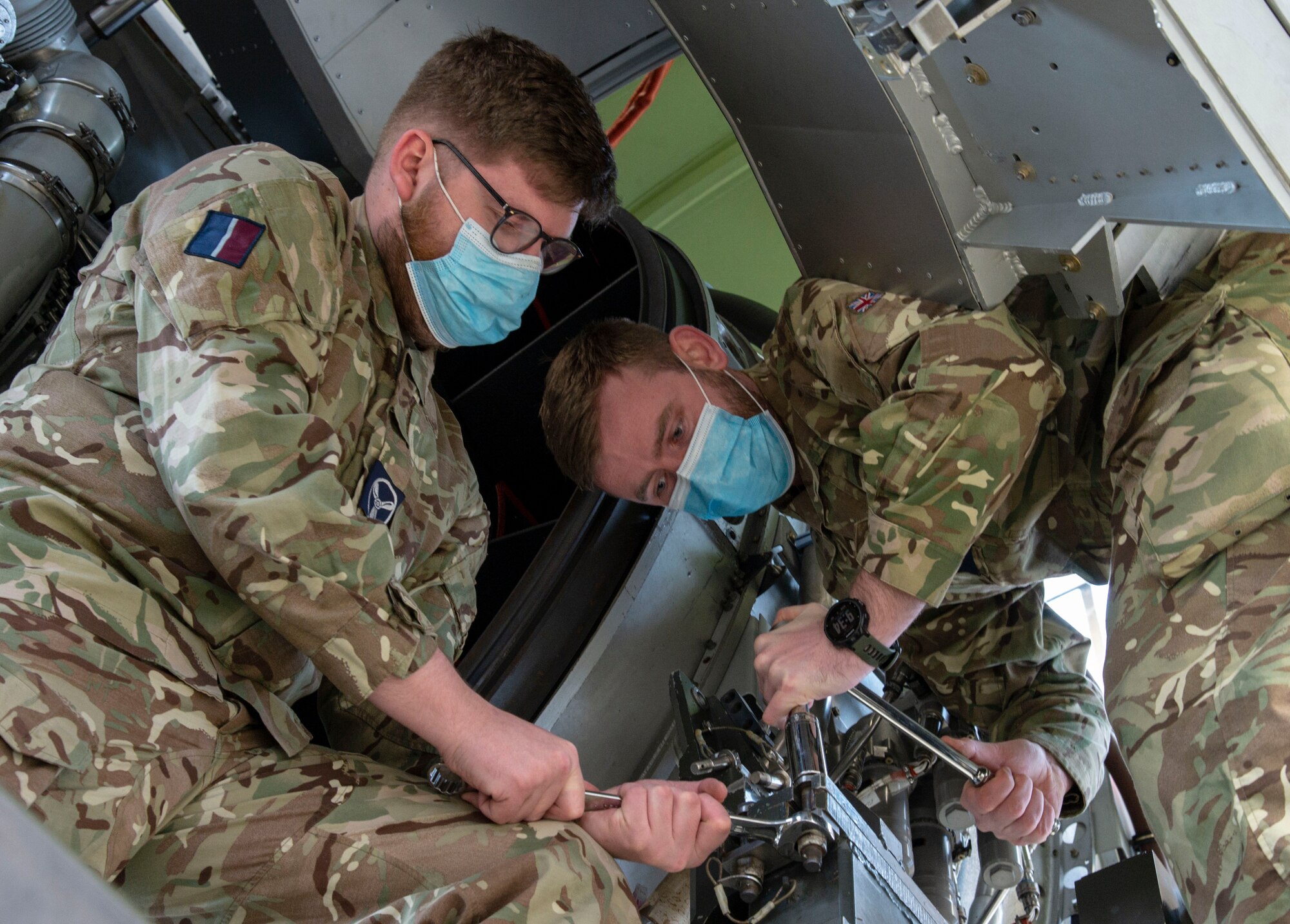 Royal Air Force Senior Aircraftman Technician Joseph Eastham holds a wrench as RAF Cpl. Ben Archer loosens a bolt from a C-17 engine trainer at Dover Air Force Base, Delaware, Feb. 15, 2022. Eastham and Archer, both C-17 Globemaster maintainers from 99 Squadron, RAF Brize Norton, United Kingdom, attended the 64-hour C-17 Engine Change course where they learned how to safely remove and reinstall the Pratt & Whitney F117-PW-100 turbofan engine. (U.S. Air Force photo by Roland Balik)