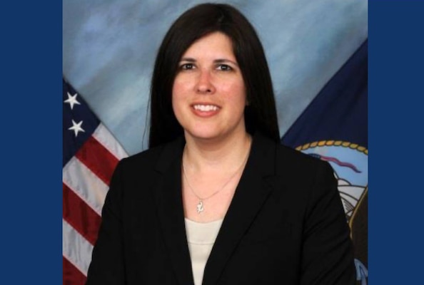 Official portrait photo of woman in her suit and white top with usa and navy flags in background