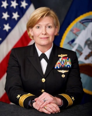 Official portrait photo of woman in her uniform with USA and navy flag in the background