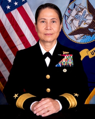 Official portrait photo of woman in her uniform with usa and navy flags in the background