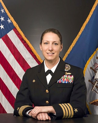 Official portrait photo of woman in her uniform with usa and navy flags in background