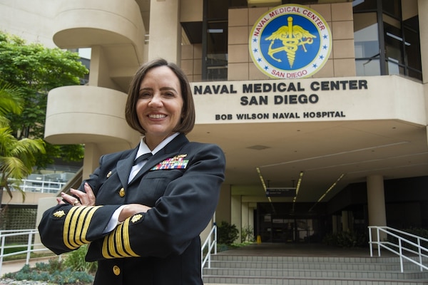 Smiling woman in her uniform standing proudly front of medical center